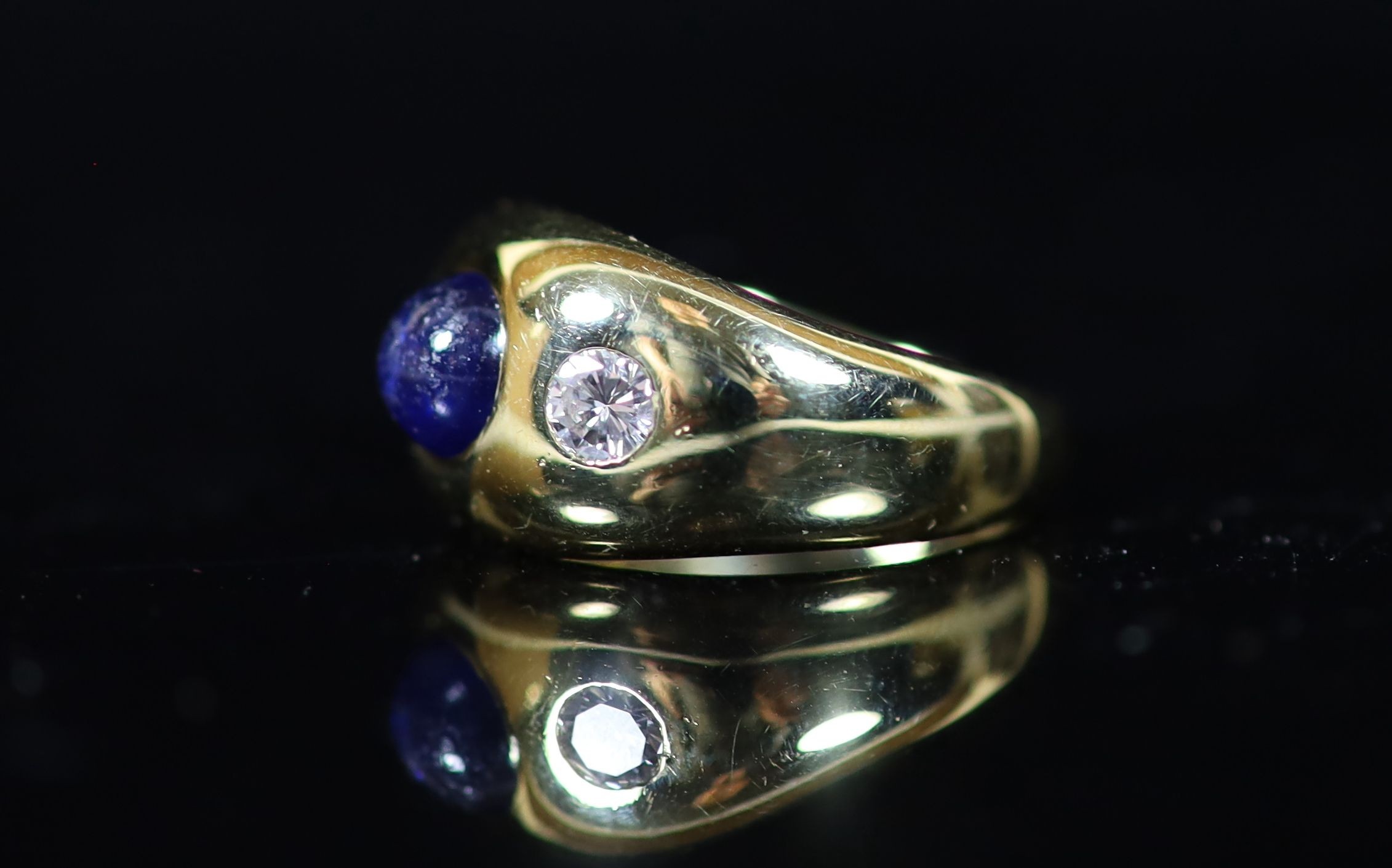 A Cartier 18ct gold , gypsy set cabochon sapphire and two stone diamond ring